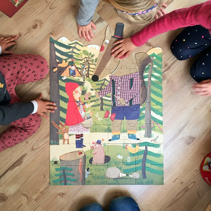 Mehrere Kinder die ein Puzzle von Rotkäppchen und dem bösen Wolf von Londji am legen sind.